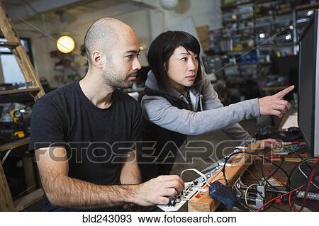Stock Image - Man and woman working with electronics in workshop. Fotosearch