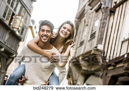 Stock Photo - Man carrying woman piggyback in city. Fotosearch