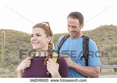Stock Image - Man helping woman with backpack. Fotosearch