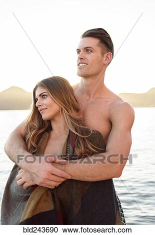 Man hugging woman wrapped in blanket at river View Large Photo Image Stock Image - Man hugging woman wrapped in blanket at river. Fotosearch