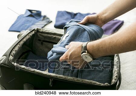 Man packing sweater into suitcase View Large Photo Image Stock Photo - Man packing sweater into suitcase. Fotosearch