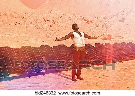 Stock Image - Man standing in sunny desert near solar panels. Fotosearch