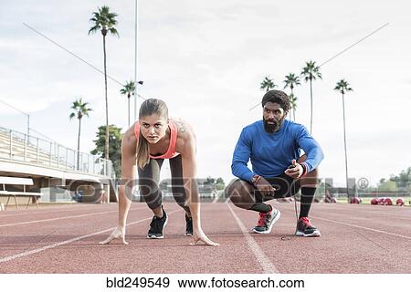 Stock Photo - Man timing woman on track in starting position. Fotosearch