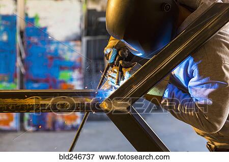 Stock Photo - Man welding metal sculpture. Fotosearch