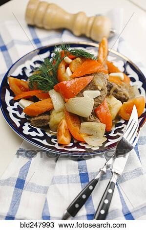 Stock Image - Meat and vegetables on plate with fork and knife. Fotosearch