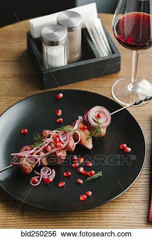 Stock Photograph - Meat on skewer with pomegranate seeds and red wine . Fotosearch