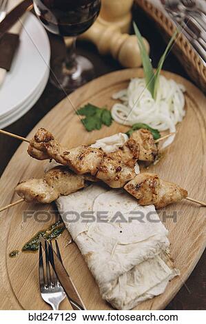 Stock Photo - Meat on skewers with bread on tray. Fotosearch