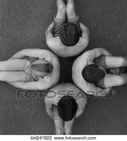 Stock Image - Men sitting back to back on ground. Fotosearch