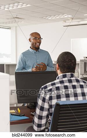 Stock Photo - Men talking in office near computer. Fotosearch