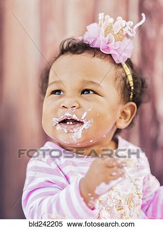 Stock Photography - Messy Mixed Race baby eating birthday cake. Fotosearch