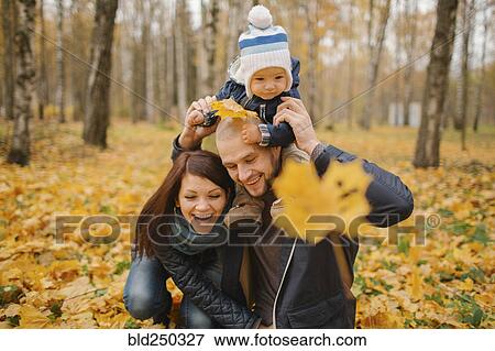 Stock Photo - Middle Eastern couple carrying baby son in park in autumn. Fotosearch