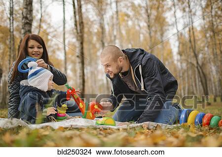 Middle Eastern couple playing with baby son in park in autumn View Large Photo Image Picture - Middle Eastern couple playing with baby son in park in autumn. Fotosearch