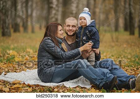 Stock Photo - Middle Eastern couple sitting in park with baby son in autumn. Fotosearch