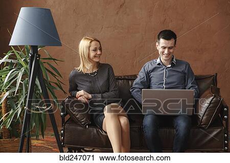 Middle Eastern couple sitting on sofa using laptop View Large Photo Image Stock Image - Middle Eastern couple sitting on sofa using laptop. Fotosearch