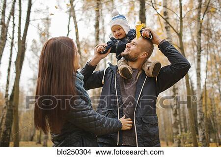 Picture - Middle Eastern father carrying baby son in autumn. Fotosearch