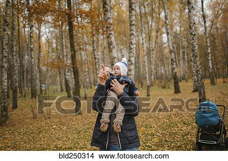 Picture - Middle Eastern father holding baby son and pointing in autumn. Fotosearch