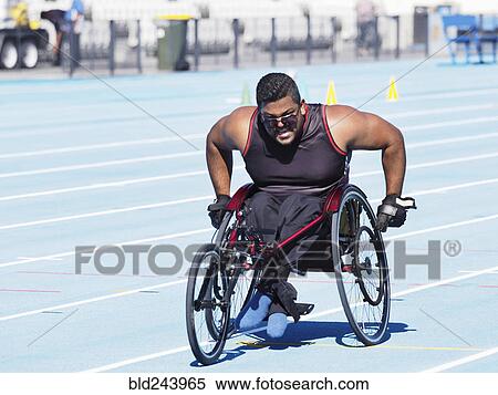 Stock Photography - Middle Eastern man racing in wheelchair on track. Fotosearch