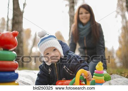 Stock Photography - Middle Eastern mother watching baby son playing with toys in park. Fotosearch