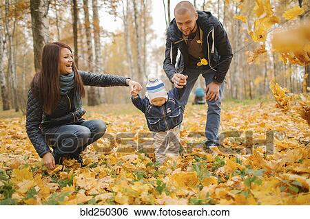 Stock Photograph - Middle Eastern parents walking with baby son in autumn. Fotosearch