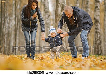 Stock Photography - Middle Eastern parents walking with baby son in autumn. Fotosearch