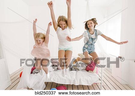 Stock Photo - Middle Eastern sisters jumping off bed. Fotosearch