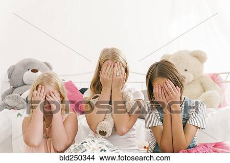 Middle Eastern sisters sitting on floor in bedroom covering eyes View Large Photo Image Picture - Middle Eastern sisters sitting on floor in bedroom covering eyes. Fotosearch