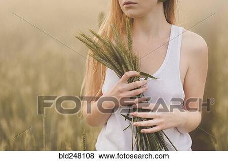 Middle Eastern teenage girl holding wheat in field View Large Photo Image Stock Photo - Middle Eastern teenage girl holding wheat in field. Fotosearch