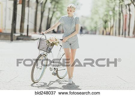 Middle Eastern woman holding bouquet and walking bicycle View Large Photo Image Stock Photo - Middle Eastern woman holding bouquet and walking bicycle. Fotosearch