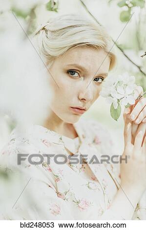 Stock Image - Middle Eastern woman holding flowers on tree. Fotosearch