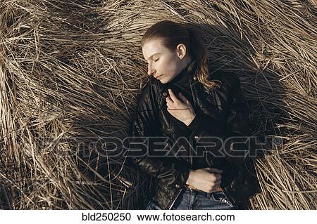 Stock Image - Middle Eastern woman resting in tall grass. Fotosearch
