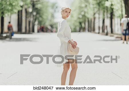 Middle Eastern woman standing in street holding purse View Large Photo Image Stock Photo - Middle Eastern woman standing in street holding purse. Fotosearch