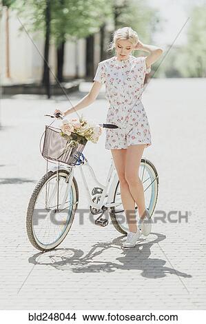 Picture - Middle Eastern woman standing near bicycle. Fotosearch