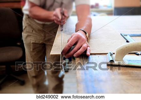 Stock Image - Midsection of Caucasian man cutting panel with saw. Fotosearch