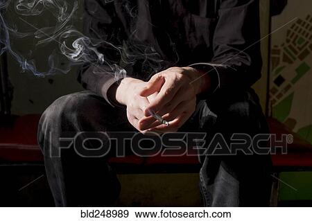 Stock Photo - Midsection of Caucasian man smoking cigarette. Fotosearch