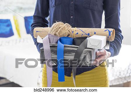 Stock Photograph - Midsection of Caucasian woman holding box and ribbons. Fotosearch
