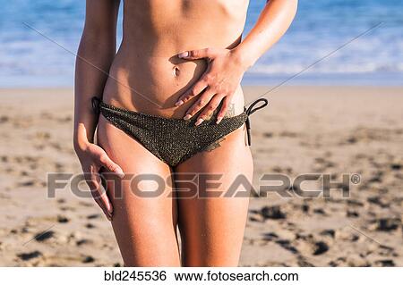 Stock Photograph - Midsection of Caucasian woman wearing bikini on beach. Fotosearch