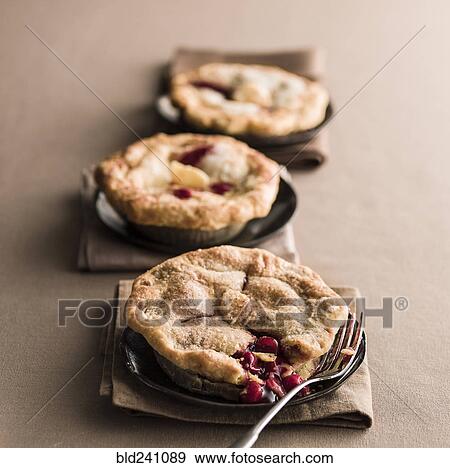 Stock Photo - Miniature cherry pies with fork. Fotosearch