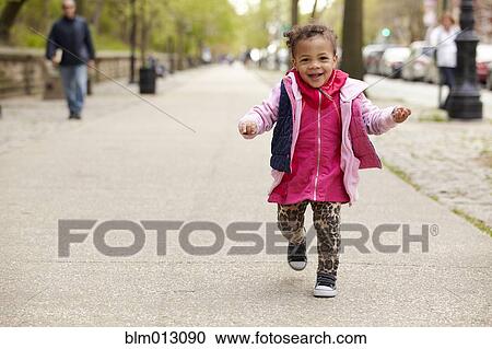 Stock Image - Mixed race baby girl walking on sidewalk. Fotosearch