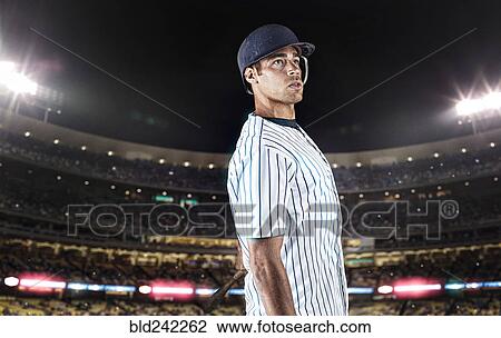Stock Image - Mixed race baseball player standing in stadium. Fotosearch