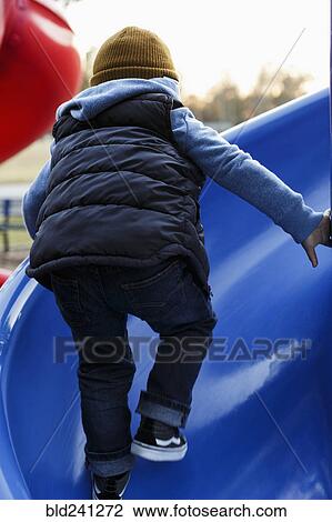 Mixed Race boy climbing on blue playground slide View Large Photo Image Stock Image - Mixed Race boy climbing on blue playground slide. Fotosearch
