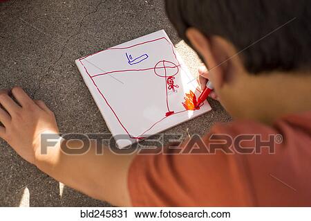 Stock Image - Mixed Race boy drawing on paper with marker. Fotosearch