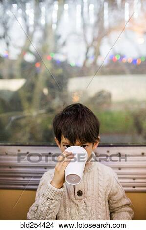Mixed Race boy drinking from cup near train window View Large Photo Image Picture - Mixed Race boy drinking from cup near train window. Fotosearch