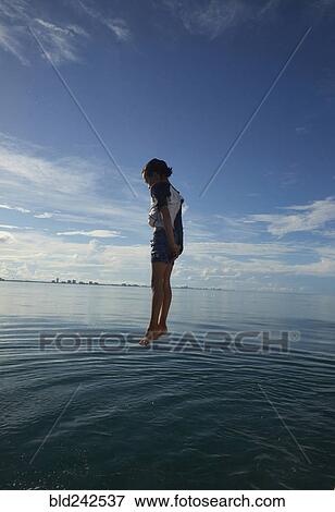 Stock Photo - Mixed Race boy jumping into ocean. Fotosearch