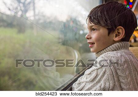 Stock Image - Mixed Race boy looking out train window. Fotosearch