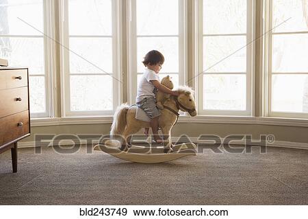 Mixed Race boy sitting on rocking horse near window View Large Photo Image Stock Photo - Mixed Race boy sitting on rocking horse near window. Fotosearch