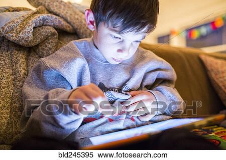 Mixed Race boy using digital tablet at night View Large Photo Image Stock Photography - Mixed Race boy using digital tablet at night. Fotosearch