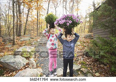 Picture - Mixed Race brother and sister balancing flowers on heads. Fotosearch