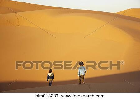 Stock Photo - Mixed race brothers walking in desert. Fotosearch