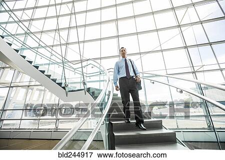 Stock Photo - Mixed Race businessman descending staircase. Fotosearch