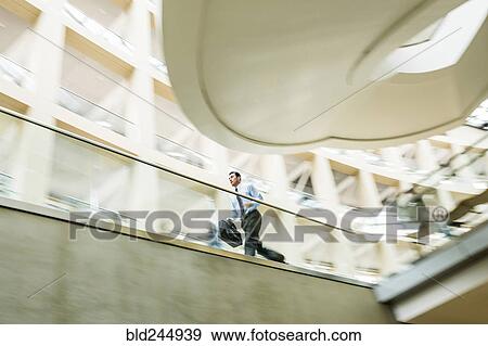 Mixed Race businessman running late in lobby View Large Photo Image Stock Photo - Mixed Race businessman running late in lobby. Fotosearch